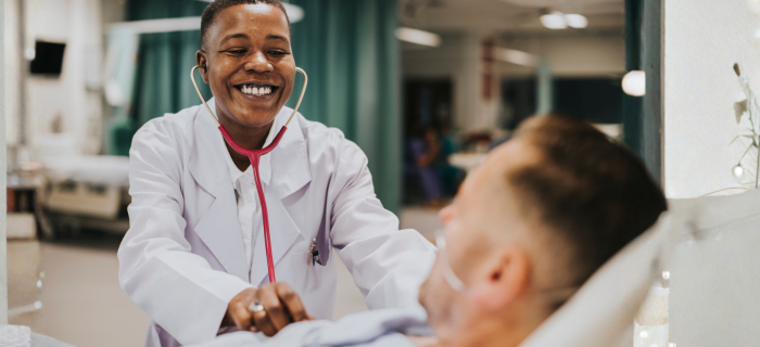Smiling female doctor holding a stethoscope to a young boy's chest in a hospital setting