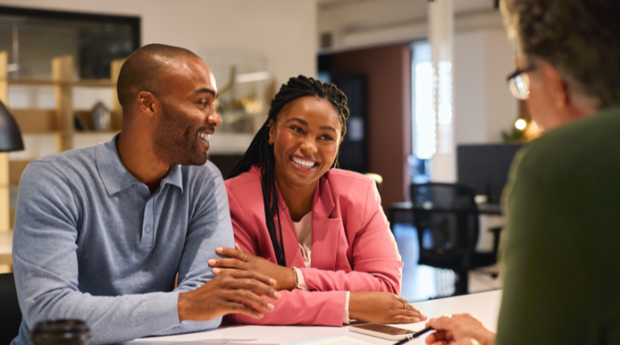 Happy couple discussing estate planning and Will structure with a financial advisor in an office