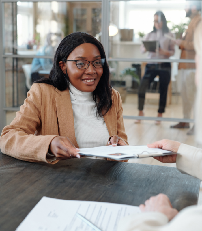 Woman signing a Last Will and Testament document on a desk during estate planning
