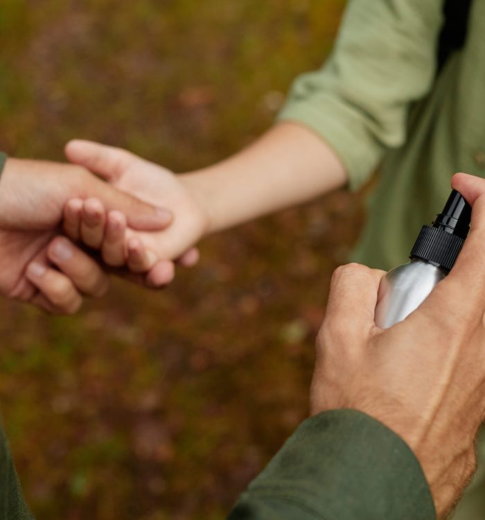 Close-up view of hands using sanitizing spray bottle in outdoor setting for good hygiene practices and cleanliness